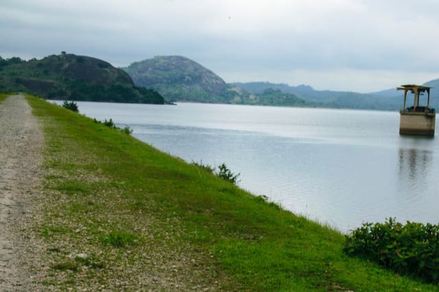 Landscape photograph. Astound with the composition; green levee, water body, rocks and the skyline.