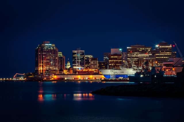 Illuminated Halifax skyline along the waterfront, featuring striking city lights reflected in the harbor at night.