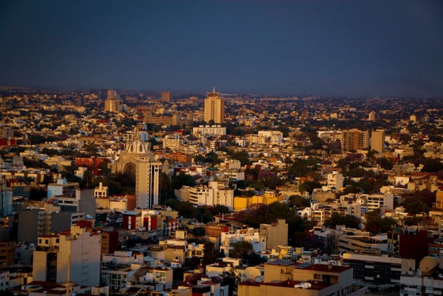 Aerial view of Guadalajara cityscape during sunset, showcasing vibrant buildings and warm colors.