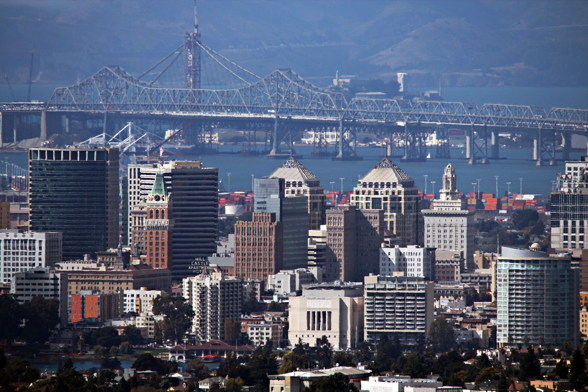 The Oakland skyline as seen from the Oakland hills. Oakland, CA has a population of about 400,000 and functions as the principal port city of Northern California. Both the old and new eastern span of the San Francisco-Oakland Bay Bridge can be seen in the background. It carries over 270,000 vehicles each day between the San Francisco Peninsula and the East Bay.