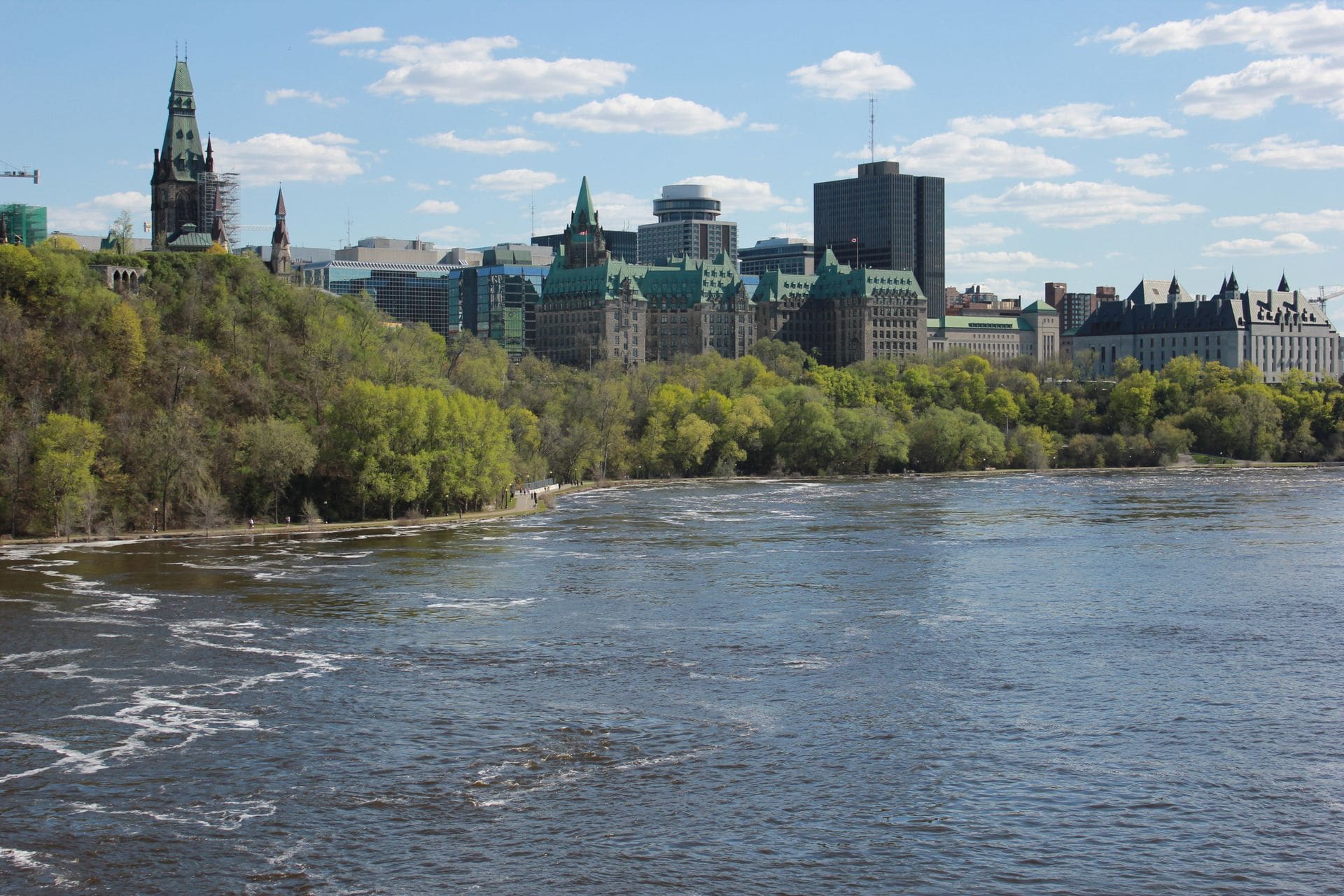 A scenic view of Ottawa's Parliament buildings and the Ottawa River on a clear day.