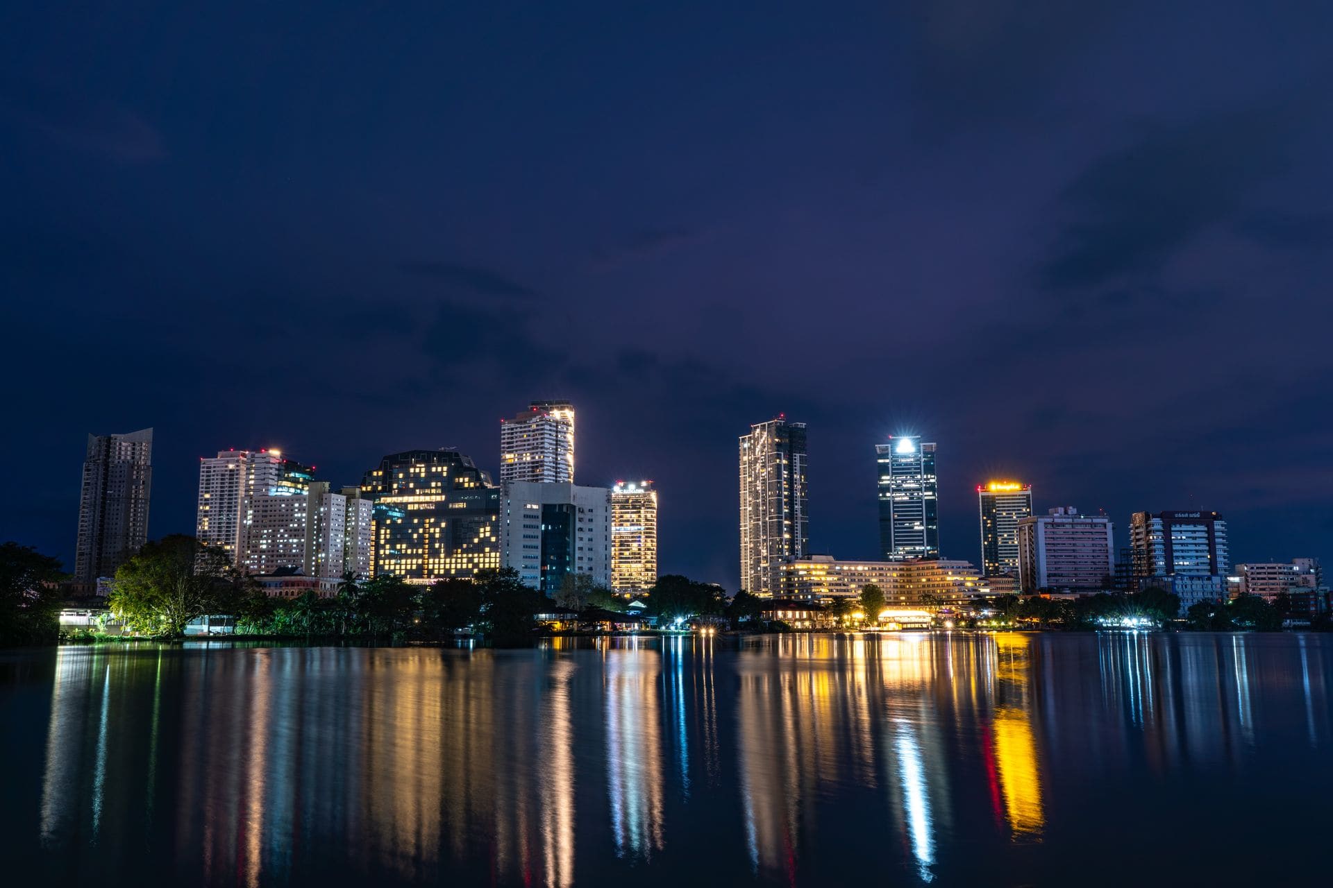 Stunning night view of Colombo skyline reflecting in serene water. Captivating city lights create a vibrant atmosphere.