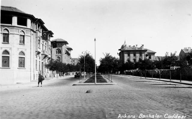 www.archives.saltresearch.org/R/QETRM7R3C38IBCM5LGHKSXI6A... Bankalar Street was the first street to be built in district of Ulus during the construction of the new capitol Ankara. As the original financial district of Ankara, the street was composed of large monumental buildings, mostly built between 1926-1934. The first building to go up in 1926 was the Ottoman Bank, designed by Guilio Mongeri. For the same street Mongeri also designed the İş Bank General Headquarters and Ziraat Bank. Being major examples of the First National Architecture Movement, these buildings stand out for their cratfmanship as well as their use of classical Ottoman forms. Construction contnued with the designs of Clemens Holzmeister in 1930-1934 for the Central Bank and the Bank of Estates and Orphans. Differing from the previous buildings, these two banks have refined classical characteristics. SALT Research, Photography Archive Ulus’ta yer alan Bankalar Caddesi, Ankara’nın başkent ilan edilmesinin ardından yapılaşmanın ilk başladığı yerdir. Başkentin finans bölgesi olması dolayısıyla caddede, 1926-1934 yıllarında yapılmış görkemli binalar yer alır. 1926’da Guilio Mongeri tarafından tasarlanan Osmanlı Bankası ile başlayan yapılaşma, yine Mongeri’nin İş Bankası ve Ziraat Bankası binalarıyla devam eder. Birinci Ulusal Mimarlık akımının tipik birer örneği olan binalar, ince işçiliklerinin yanı sıra klasik Osmanlı biçimlerinin kullanımıyla dikkati çeker. Bunları, 1930-1934 yıllarında mimar Clemens Holzmeister tarafından yapılmış olan Merkez Bankası ile Emlak ve Eytam Bankası binaları izler. Bu binalar, öncekilerden farklı olarak sadeleştirilmiş klasisist özelliklere sahiptir. SALT Araştırma, Fotoğraf Arşivi