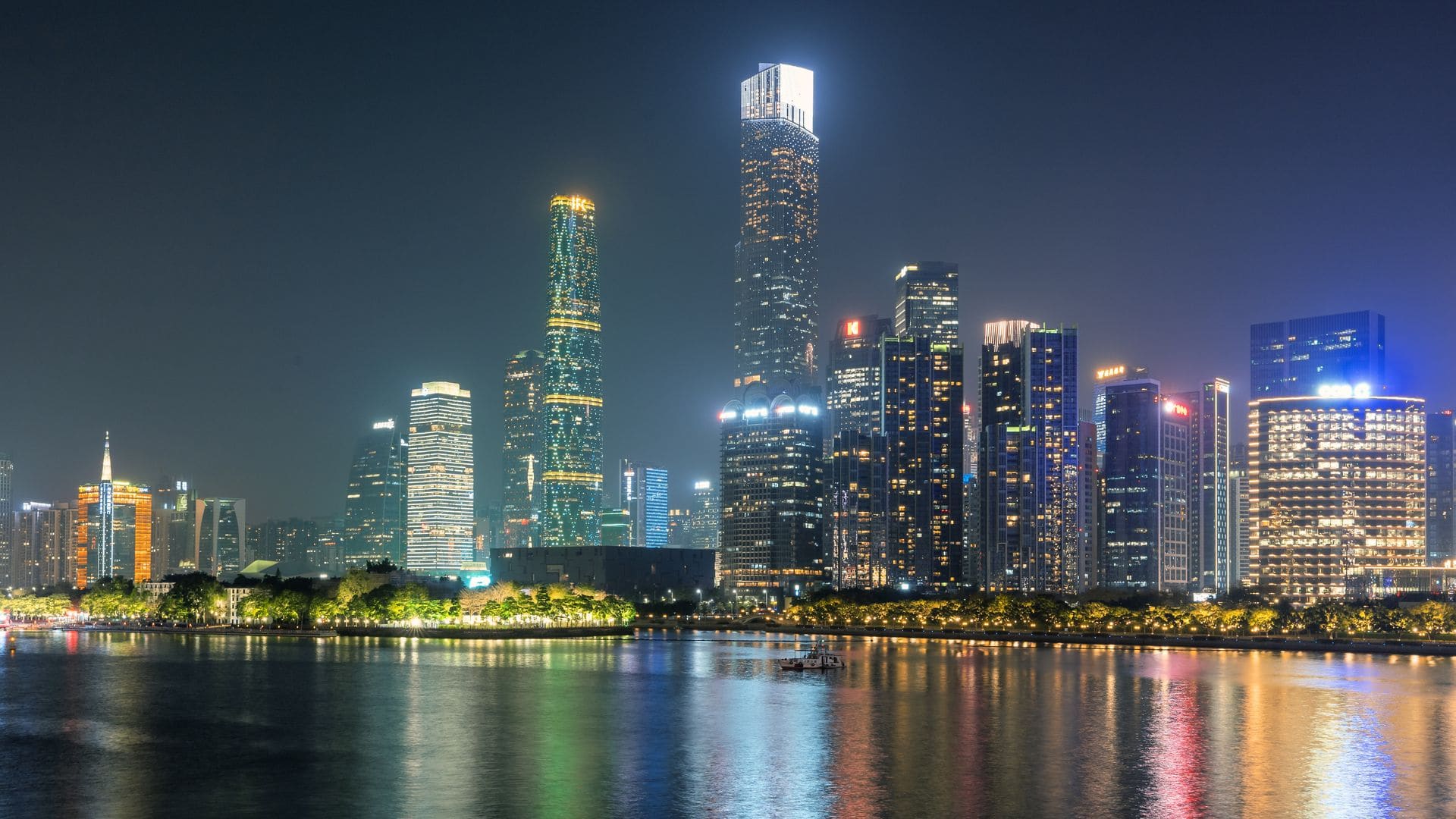 Illuminated skyscrapers of Guangzhou reflecting on the water under a night sky.