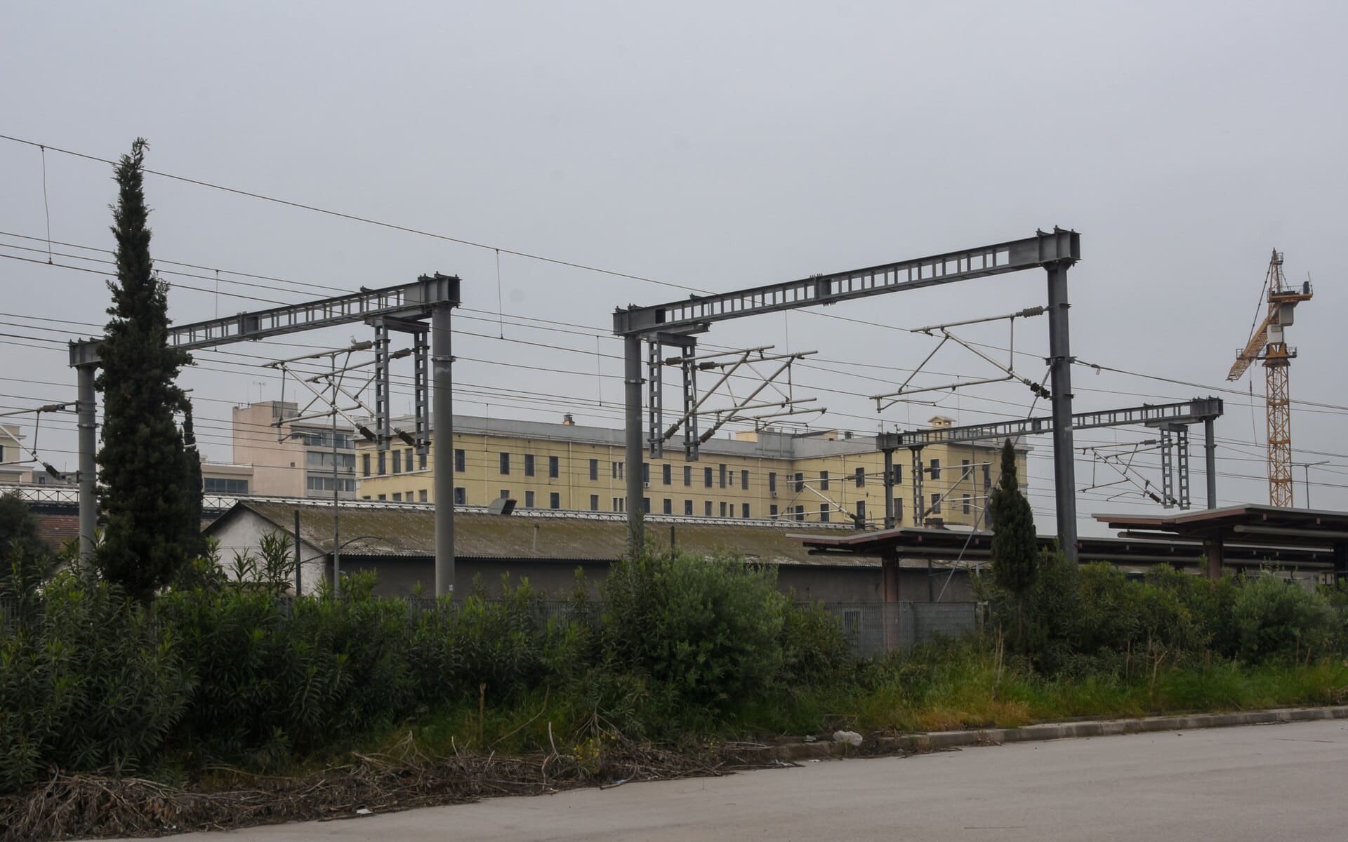 500px provided description: Just before approaching the terminal station of the suburban railway. In the background, the yellow building is the metro line 1 building and station. [#sky ,#train ,#cityscape ,#building ,#plant ,#railway station ,#metro station ,#Aghia Sophia ,#suburban railway ,#Pireas ,#electricity wire