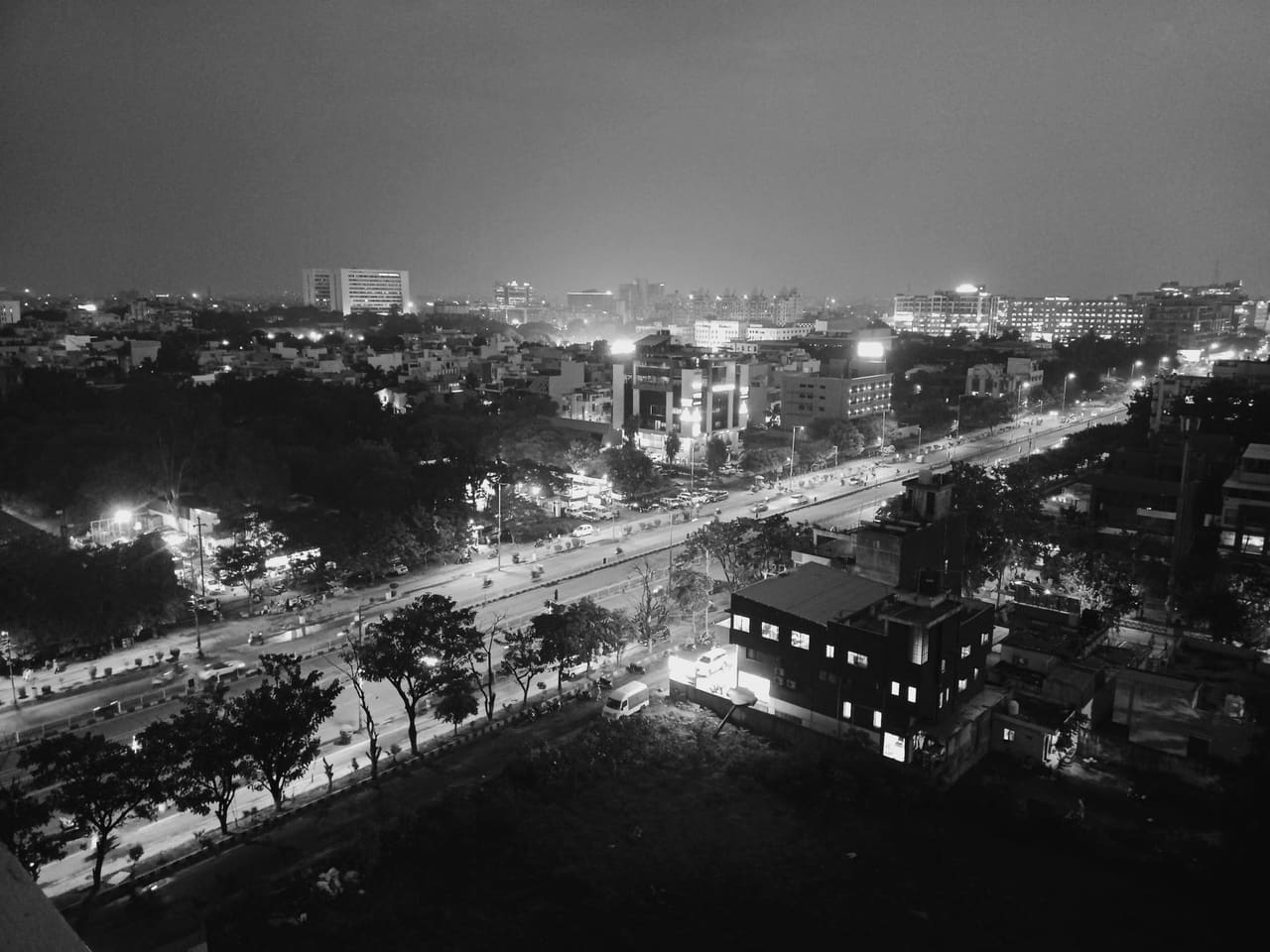 Black and white aerial view of Indore cityscape at night, showcasing urban streets and buildings.