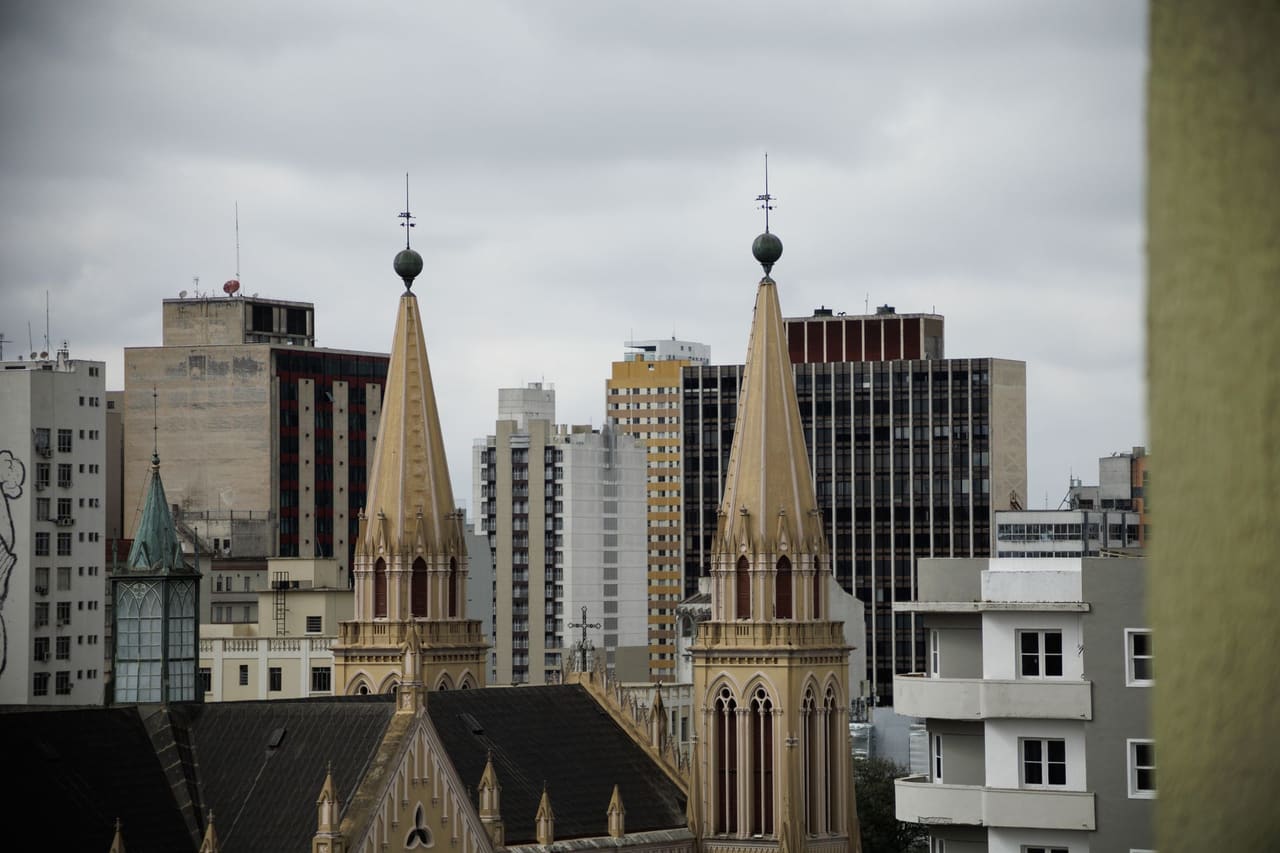 Skyline view of Curitiba with historic church spires against modern buildings.