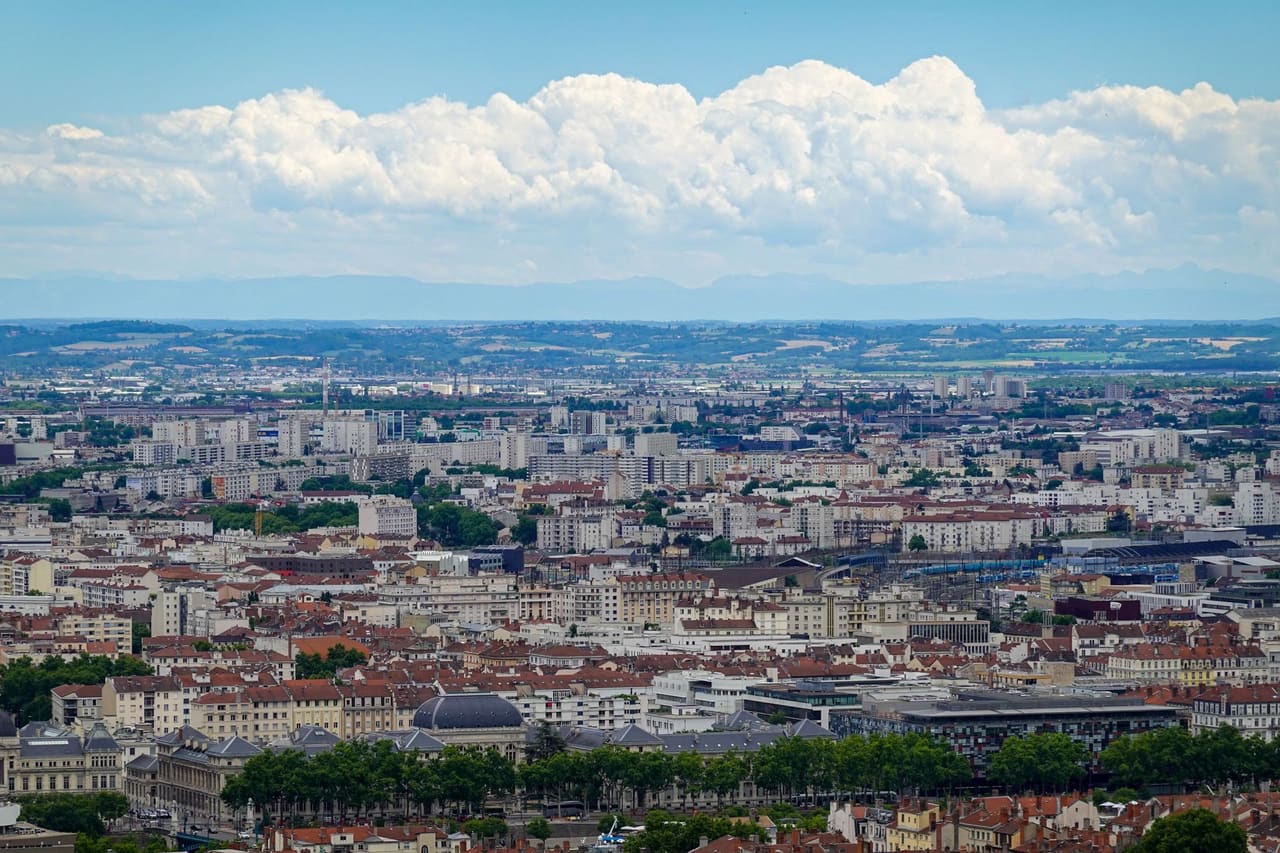 Aerial view of Lyon showcasing the sprawling urban landscape under a vibrant blue sky.
