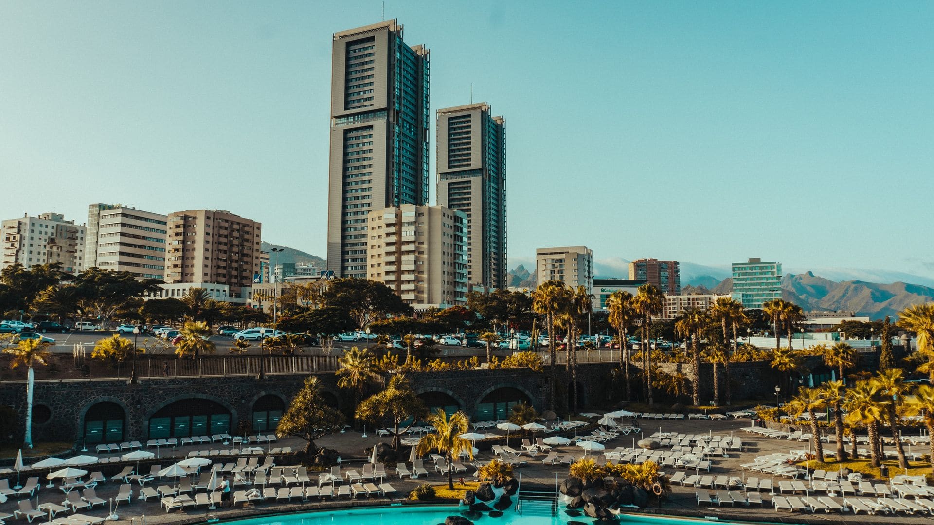 A scenic urban skyline with towering buildings and a resort pool in foreground.