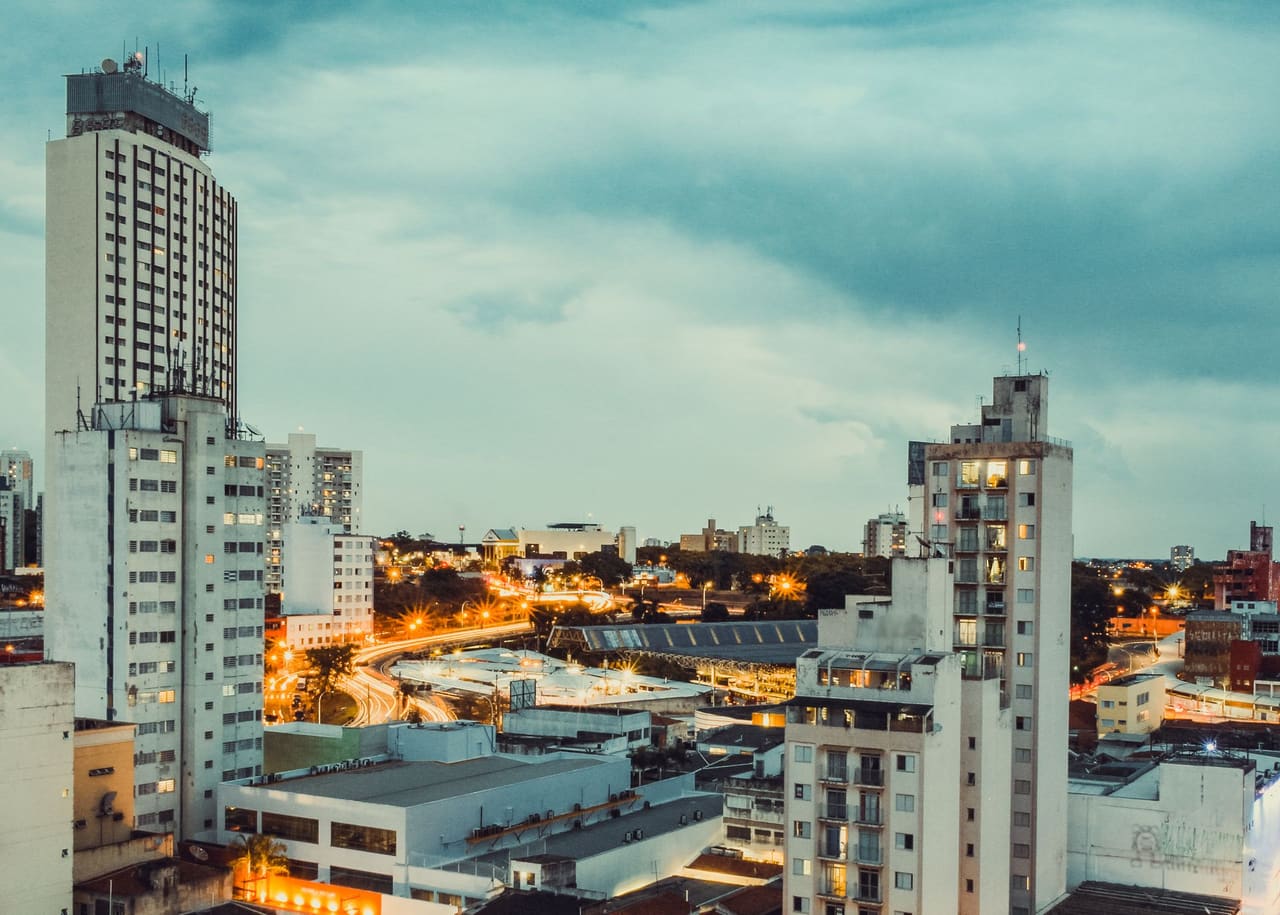 A vibrant cityscape of Campinas, Brazil, showcasing illuminated skyscrapers at dusk.
