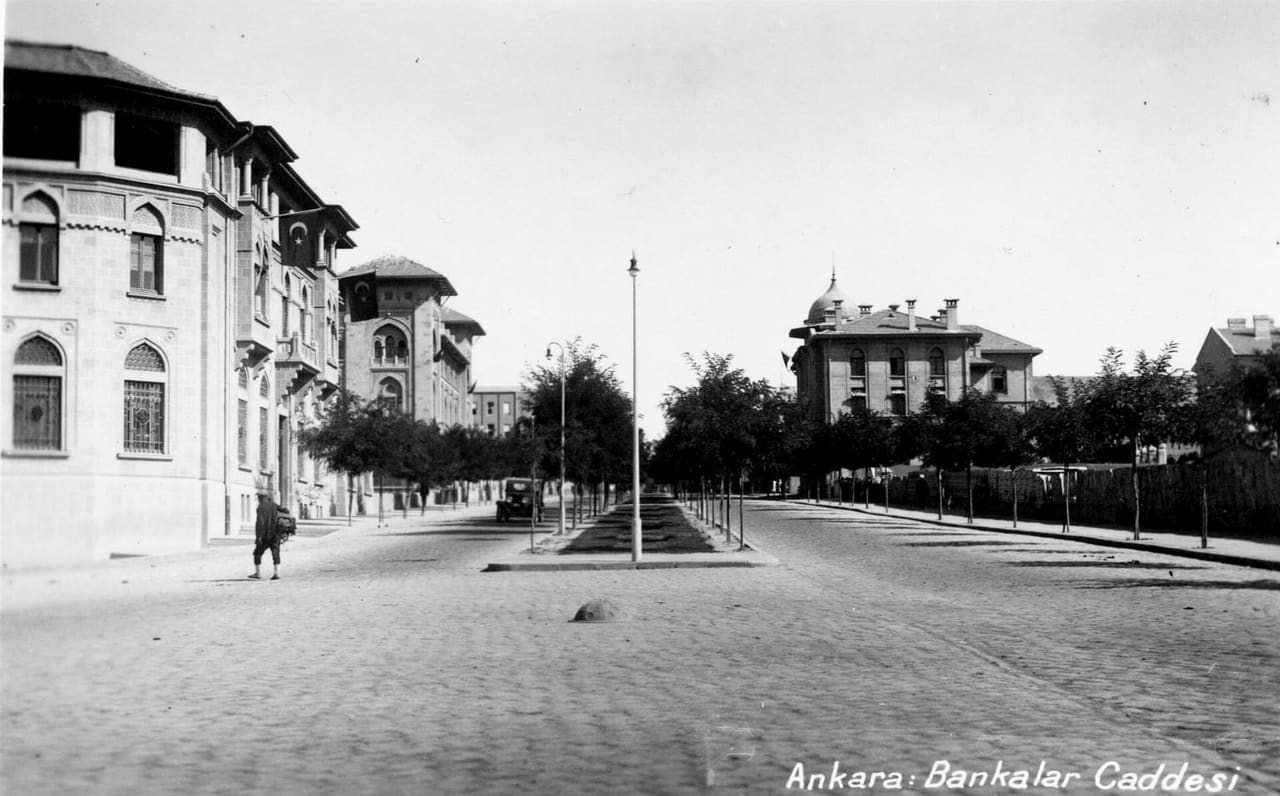 www.archives.saltresearch.org/R/QETRM7R3C38IBCM5LGHKSXI6A... Bankalar Street was the first street to be built in district of Ulus during the construction of the new capitol Ankara. As the original financial district of Ankara, the street was composed of large monumental buildings, mostly built between 1926-1934. The first building to go up in 1926 was the Ottoman Bank, designed by Guilio Mongeri. For the same street Mongeri also designed the İş Bank General Headquarters and Ziraat Bank. Being major examples of the First National Architecture Movement, these buildings stand out for their cratfmanship as well as their use of classical Ottoman forms. Construction contnued with the designs of Clemens Holzmeister in 1930-1934 for the Central Bank and the Bank of Estates and Orphans. Differing from the previous buildings, these two banks have refined classical characteristics. SALT Research, Photography Archive Ulus’ta yer alan Bankalar Caddesi, Ankara’nın başkent ilan edilmesinin ardından yapılaşmanın ilk başladığı yerdir. Başkentin finans bölgesi olması dolayısıyla caddede, 1926-1934 yıllarında yapılmış görkemli binalar yer alır. 1926’da Guilio Mongeri tarafından tasarlanan Osmanlı Bankası ile başlayan yapılaşma, yine Mongeri’nin İş Bankası ve Ziraat Bankası binalarıyla devam eder. Birinci Ulusal Mimarlık akımının tipik birer örneği olan binalar, ince işçiliklerinin yanı sıra klasik Osmanlı biçimlerinin kullanımıyla dikkati çeker. Bunları, 1930-1934 yıllarında mimar Clemens Holzmeister tarafından yapılmış olan Merkez Bankası ile Emlak ve Eytam Bankası binaları izler. Bu binalar, öncekilerden farklı olarak sadeleştirilmiş klasisist özelliklere sahiptir. SALT Araştırma, Fotoğraf Arşivi