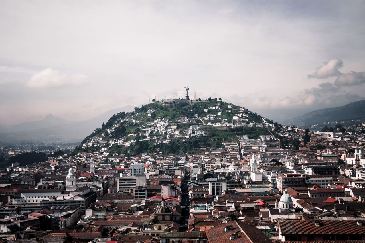 Aerial view of Quito featuring Panecillo Hill and Virgin statue, capturing historic architecture and vibrant cityscape.